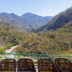 Scenic mountain valley view from a balcony overlooking green hills and a winding road for adventure sports in Rishikesh