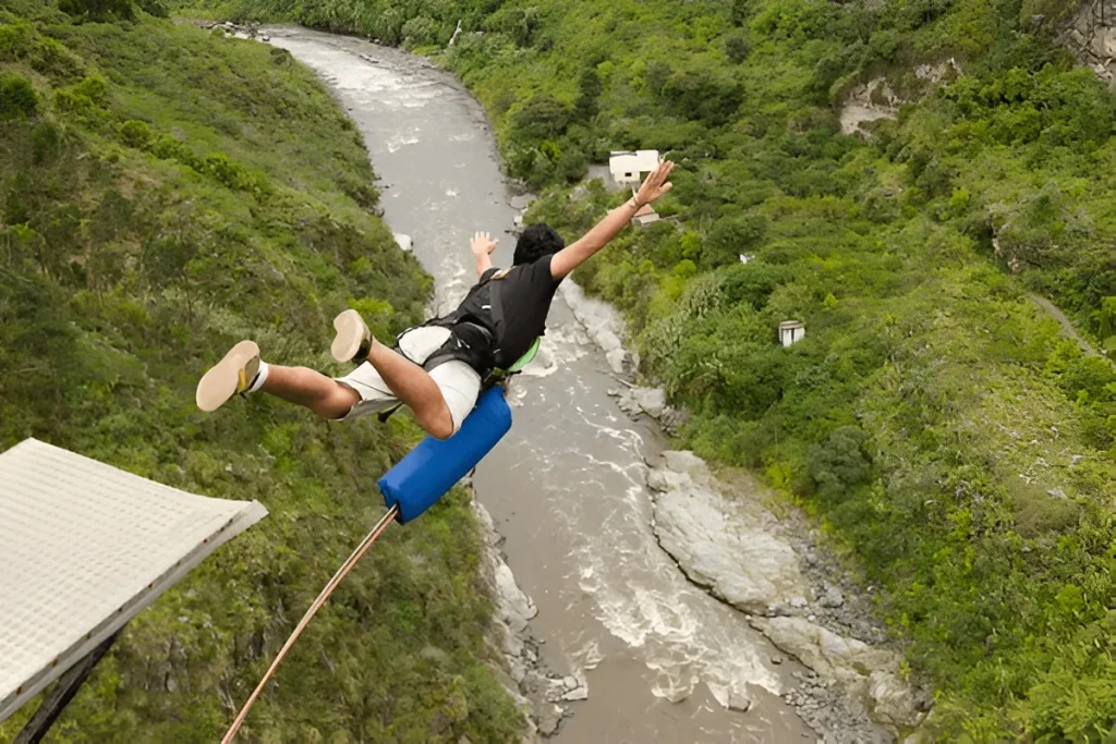 Person bungee jumping over river in green valley